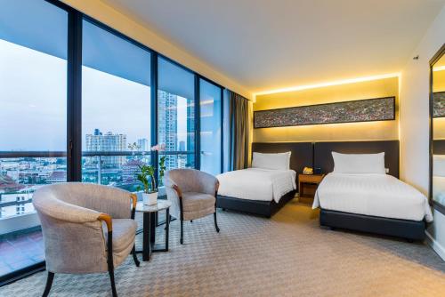 a hotel room with two beds and a table and chairs at Chatrium Residence Sathon Bangkok in Bangkok