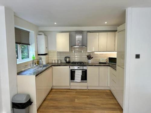 a kitchen with white cabinets and a stove top oven at Spacious 2-bed flat with free parking in Croydon