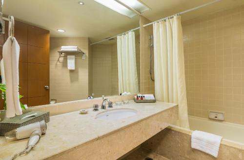 a bathroom with a sink and a large mirror at Chatrium Sathon Bangkok in Bangkok