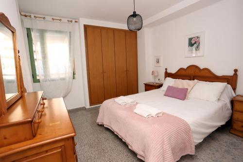 a bedroom with a large white bed and a dresser at Apartamento dos habitaciones primera línea de playa in Valencia