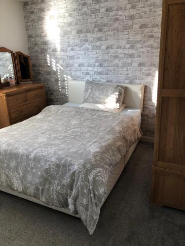 a bedroom with a bed and a brick wall at Pats house in Earlswood