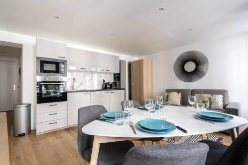 une cuisine et une salle à manger avec une table et des chaises blanches dans l'établissement Grand Boulevard 12 : Appartement Cosy 1BR- 4P, à Paris