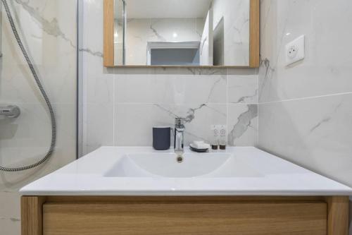 une salle de bain avec un lavabo blanc et une douche dans l'établissement Grand Boulevard 12 : Appartement Cosy 1BR- 4P, à Paris