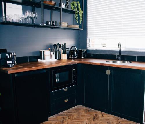 uma cozinha com armários pretos e um balcão de madeira em Rooms of Renown - The Panaretto Parlour em Leeton