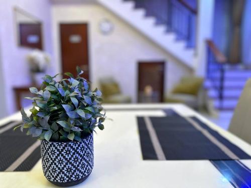 a blue and white vase with a plant on a table at Retreat Saujana rawang in Rawang