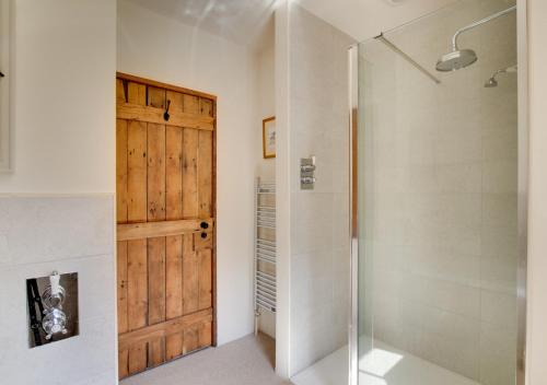 a bathroom with a shower and a wooden door at Coldwell Cottage in Beetham