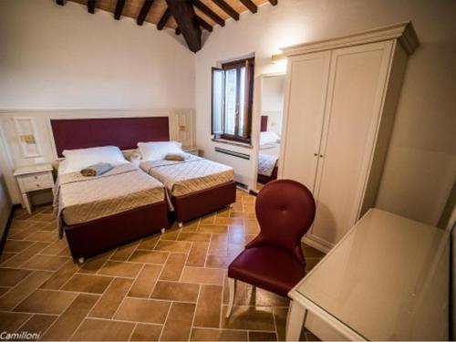 een slaapkamer met 2 bedden en een rode stoel bij Macchie San Vincenzo - Villa Privata con Piscina e Giardino ad uso esclusivo o camere in Chiusi