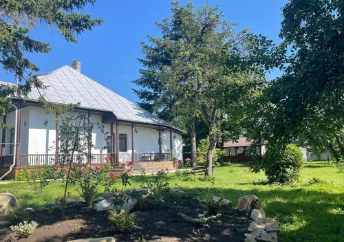une grande maison blanche avec une cour arborée dans l'établissement Casa Humulesti, fii vecinul lui Ion Creanga, à Tîrgu Neamţ