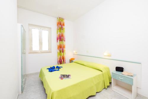 a white bedroom with a yellow bed and a window at Baia Degli Aranci Suite & Apartments in Vieste