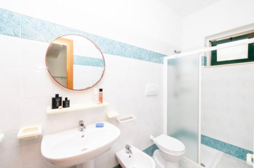 a white bathroom with a sink and a mirror at Baia Degli Aranci Suite & Apartments in Vieste