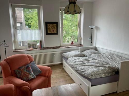 a bedroom with a bed and a chair and two windows at 2Schlafzimmer, Wohnküche&Balkon in Oberhausen