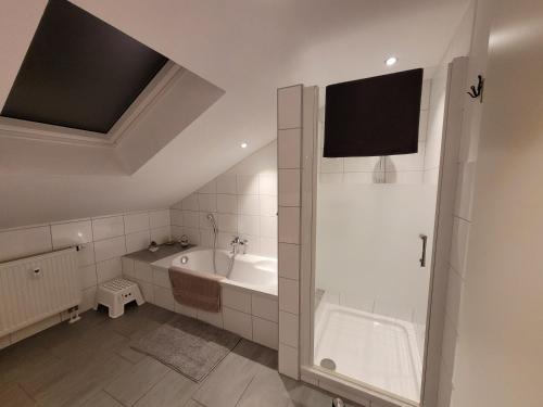 een witte badkamer met een bad en een douche bij Casa-Mandelartz in Rees