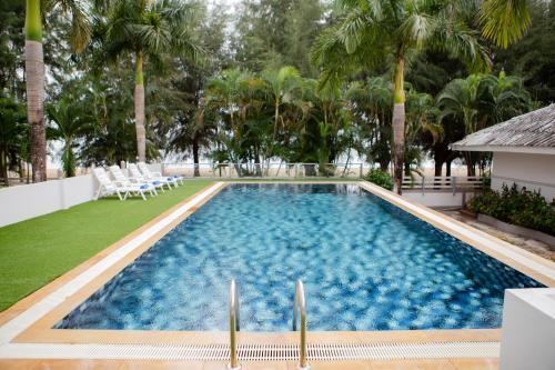 a swimming pool with chairs and palm trees at Laemsing Natural Beach Resort in Ban Pak Nam