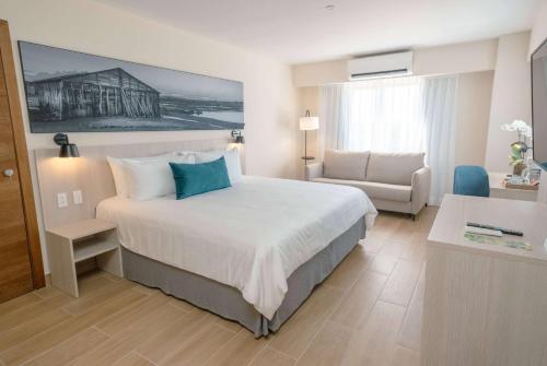 a hotel room with a large bed and a couch at Wyndham Garden El Morro Montecristi in El Rincón
