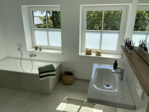 a bathroom with a sink and a tub and windows at Grüne Oase im Teutoburger Wald in Georgsmarienhütte