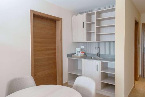 a kitchen with white cabinets and a sink and a table at Wyndham Garden El Morro Montecristi 