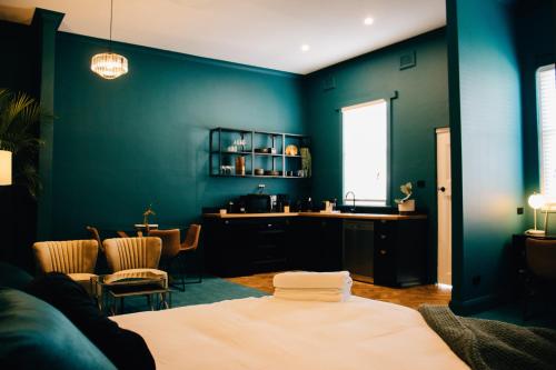 een blauwe kamer met een bed en een tafel bij Rooms of Renown - The Enterprise Suite in Leeton