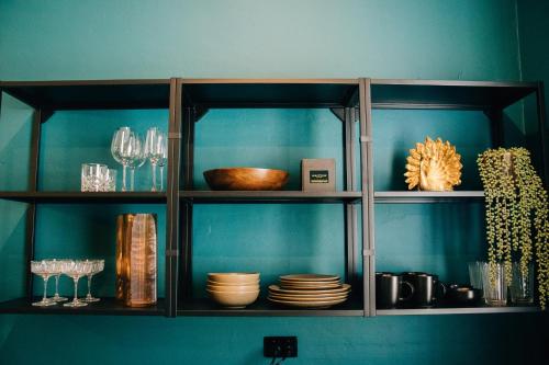 a cabinet filled with plates and glasses and dishes at Rooms of Renown - The Enterprise Suite in Leeton