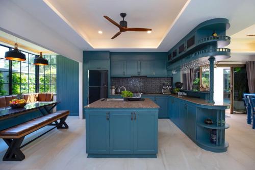 a kitchen with blue cabinets and a ceiling fan at Best Holidays - Oxygen pool, Billard, Gym! 2-Storey Tropical Villa Havana N in Kamala Beach
