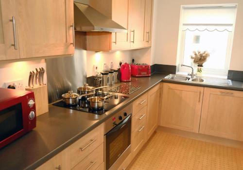 a kitchen with wooden cabinets and a red microwave at Regent - Properties Unique in Newcastle upon Tyne