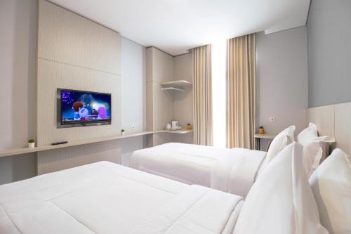 a hotel room with two beds and a flat screen tv at MIC Residence in Kejayan