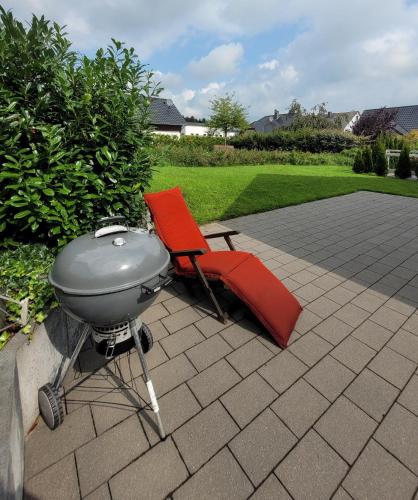 a grill and a red chair on a patio at Winterberg Chalet 21096 in Winterberg