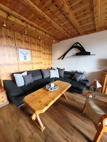 Winterberg Appartement 21077 في وينتربرغ: غرفة معيشة مع أريكة سوداء وطاولة خشبية