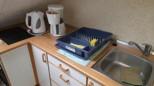 a kitchen counter with a blue tray on a sink at Ferienwohnung Tetzlaff in Neubörger