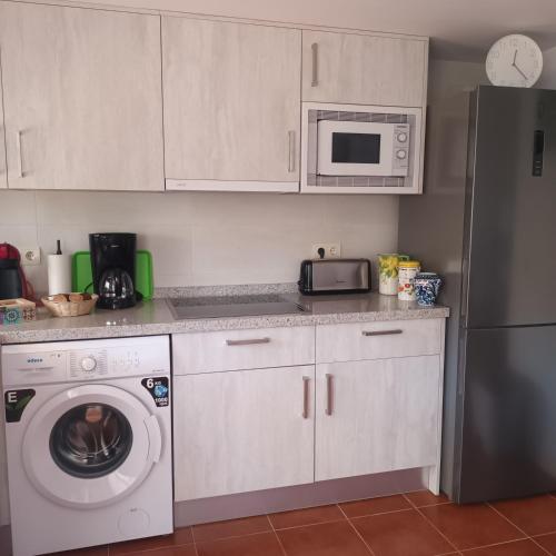 a kitchen with a washing machine and a microwave at Apartamento Bambadela in Cala del Moral