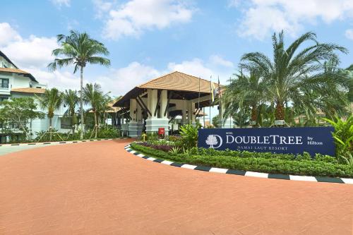un cartello di fronte a un edificio con palme di DoubleTree by Hilton Damai Laut a Lumut