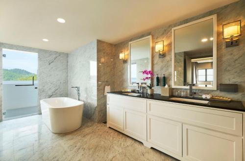 a bathroom with a tub and a sink and a mirror at DoubleTree by Hilton Damai Laut in Lumut