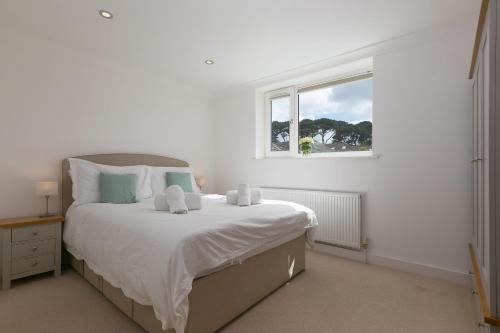 a white bedroom with a large bed with a window at Carvean in Carbis Bay