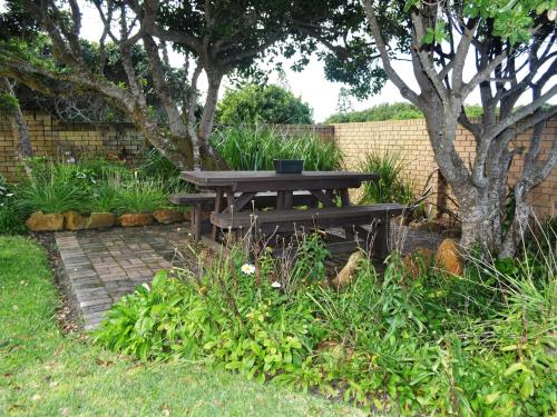 a picnic table in a garden with a tree at Great White Accommodation in Kleinbaai