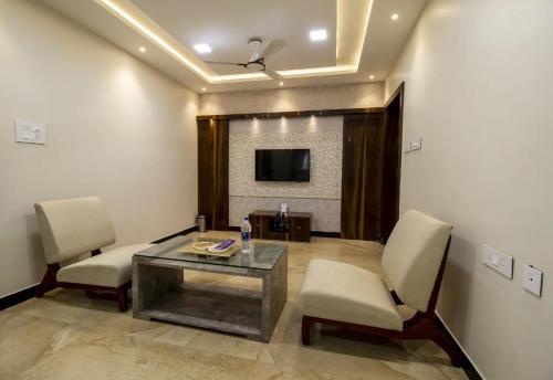 a room with a table and chairs and a tv at SR BOUTIQUE STAY SERVICE APARTMENT in Coimbatore