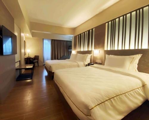 ein Hotelzimmer mit 2 Betten und einem TV in der Unterkunft The Aurora Subic Hotel Managed By HII in Olongapo