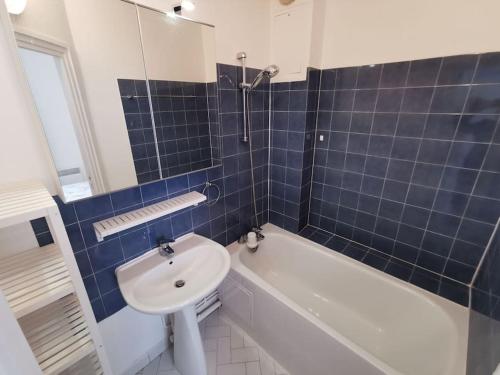 La salle de bains est pourvue de carrelage bleu, d'un lavabo et d'une baignoire. dans l'établissement Wei&Pei Apartment - St Germain En Laye Center -2min RER, à Saint-Germain-en-Laye