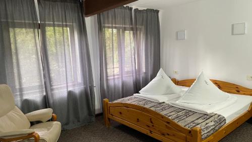 Schlafzimmer mit einem Bett, einem Stuhl und Fenstern in der Unterkunft Casa Piscu Ioanei in Braşov