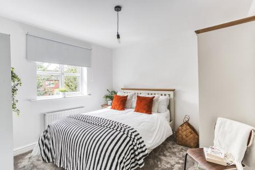 een witte slaapkamer met een bed met oranje kussens bij Urban Retreat with Park Views in Derby