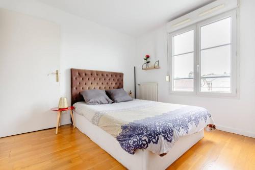 a white bedroom with a large bed and a window at Artist Retreat in Noisy-le-Grand