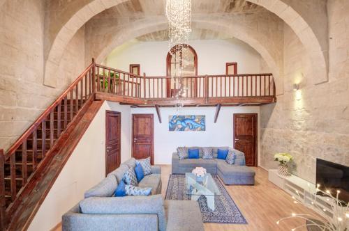 a living room with blue couches and a staircase at Valletta Waterfront Villa with Pool and Jacuzzi in Valletta