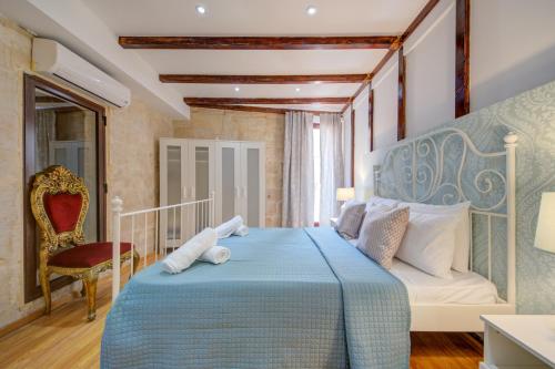 a bedroom with a blue bed and a chair at Valletta Waterfront Villa with Pool and Jacuzzi in Valletta