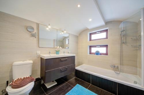 a bathroom with a toilet and a tub and a sink at Valletta Waterfront Villa with Pool and Jacuzzi in Valletta