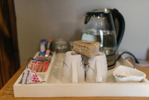 a tray with cups and a tea pot and a piece of cake at Agapé Boutique Guesthouse Bothaville in Bothaville