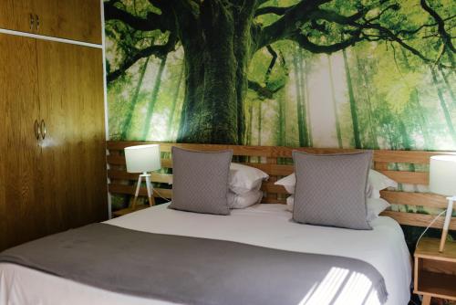 a bedroom with a bed with a tree mural on the wall at Agapé Boutique Guesthouse Bothaville in Bothaville