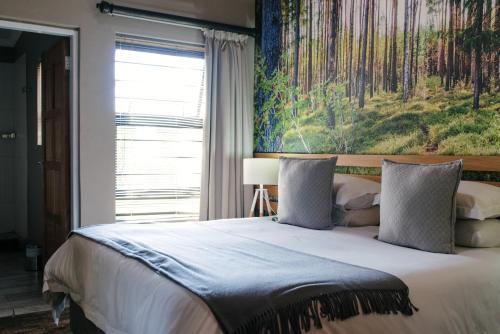 a bedroom with a large bed with a painting on the wall at Agapé Boutique Guesthouse Bothaville in Bothaville