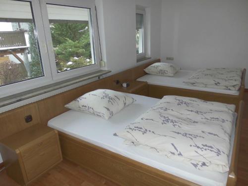 2 Betten in einem Zimmer mit 2 Fenstern in der Unterkunft Ferienwohnung Wehr in Filderstadt