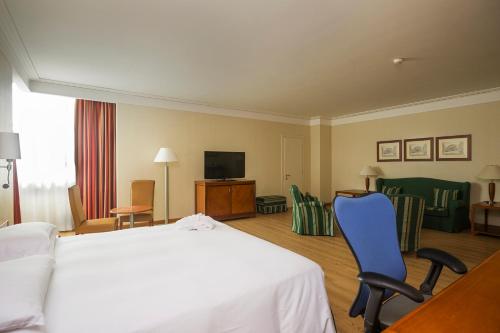 a hotel room with a bed and chairs and a television at Hilton Rome Airport in Fiumicino