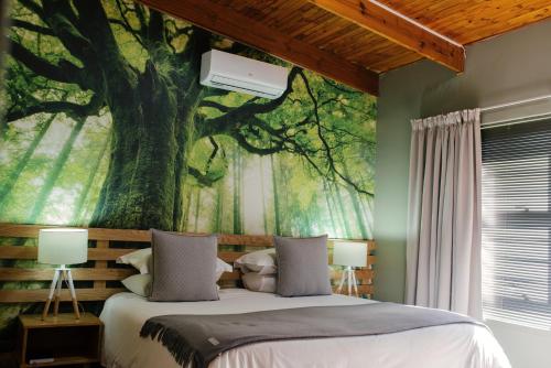 a bedroom with a large tree mural on the wall at Agapé Boutique Guesthouse Bothaville in Bothaville