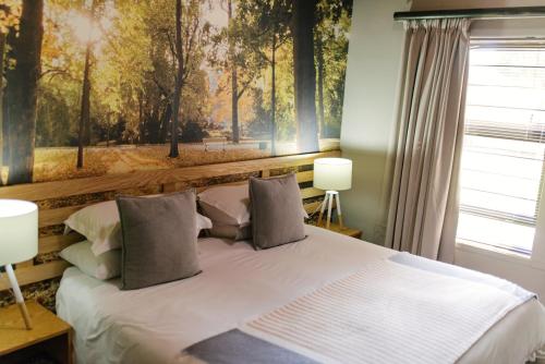 a bedroom with a bed with a painting on the wall at Agapé Boutique Guesthouse Bothaville in Bothaville