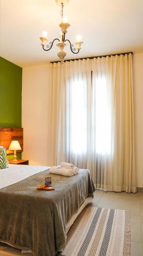 a bedroom with a bed with a chandelier and a window at Pouso da Rita - Tiradentes in Tiradentes